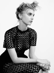 Model with updo hairstyle wearing black patterned cut-out dress against white background in a fashion portrait styled by Emily Ward