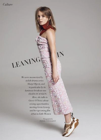 Eliza Scanlen poses in a pink floral dress with sneakers against a gray background, promoting film 'Little Women'. Editorial fashion photography.