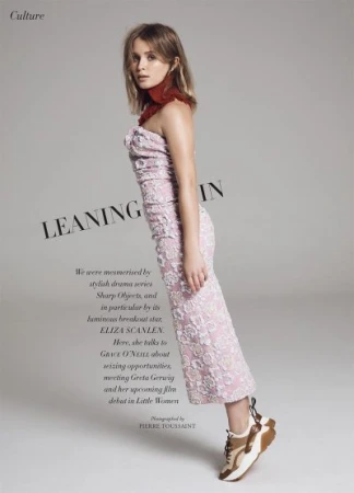 Eliza Scanlen poses in a pink floral dress with sneakers against a gray background, promoting film 'Little Women'. Editorial fashion photography.