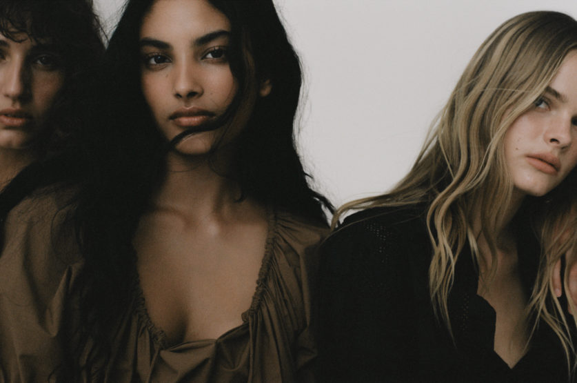 Close-up portrait of three female models with natural makeup styling against a plain white studio background.