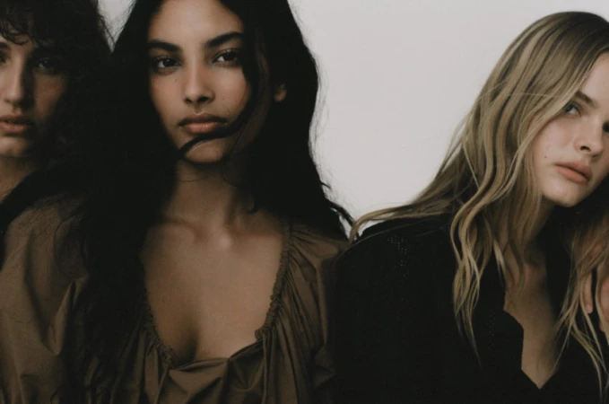 Close-up portrait of three female models with natural makeup styling against a plain white studio background.