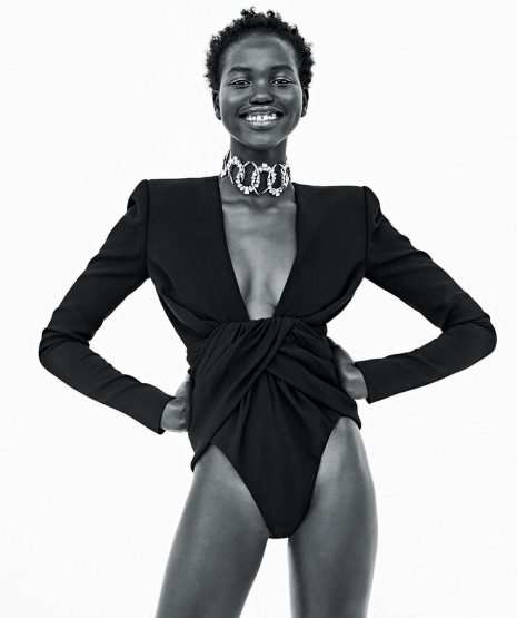 Black and white portrait of a smiling African woman in a black bodysuit with a plunging neckline and a sparkling silver choker. Fashion.