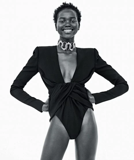 Black and white portrait of a smiling African woman in a black bodysuit with a plunging neckline and a sparkling silver choker. Fashion.