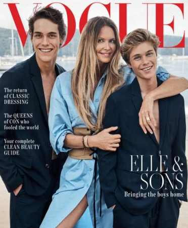 Vogue magazine cover featuring a woman in a blue dress standing between two boys in suits against a beach and water backdrop.