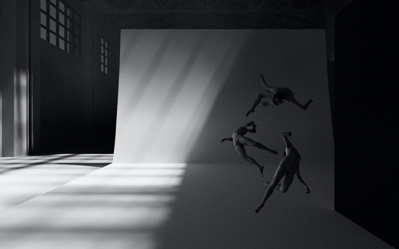 Monochrome image of three figures suspended in motion against a large curved white studio wall with dramatic diagonal light beams.