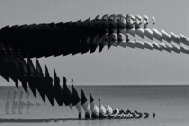 Monochrome multiple exposure image of a man stretching and bending forward against a plain studio background.