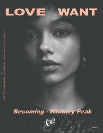 Close up portrait of a young woman with dark curly hair and earrings against a dark textured background with pink magazine typography.