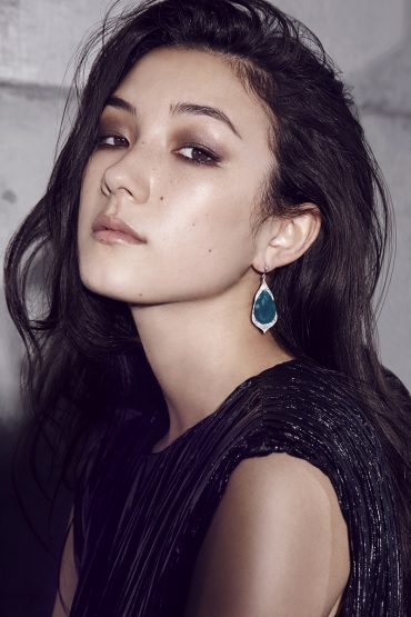 Portrait of a woman wearing a dark pleated top and teardrop earrings, with makeup by Sarah Tammer in Sydney