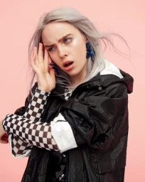 Portrait of Billie Eilish with silver hair wearing a black jacket and checkered sleeves against a pink background