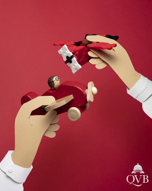 Two hands holding red toy airplanes against a red background. One toy plane is being held toward the other.