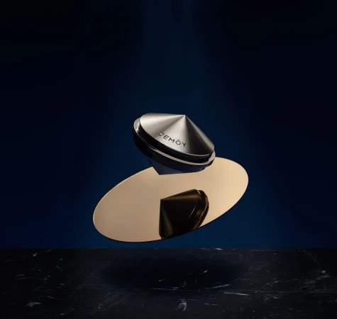 Elevated product shot showcases a metallic container and reflective gold surface on a dark marble slab against a navy backdrop.