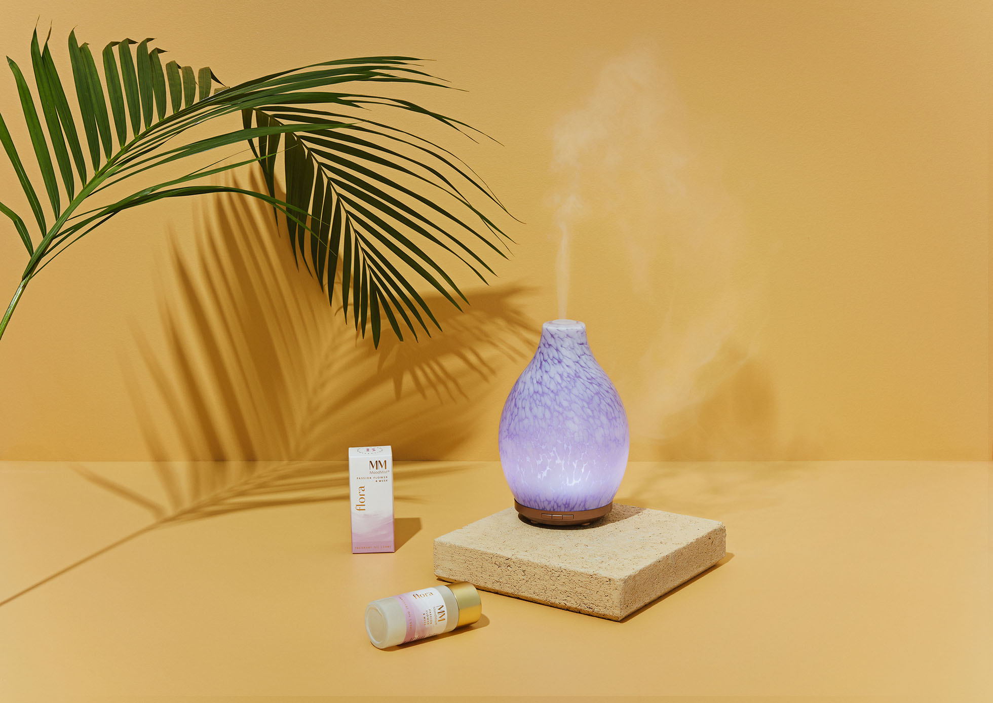 Aroma diffuser with essential oils on a beige background with palm leaf shadow. Interior wellness and home aromatherapy concept.