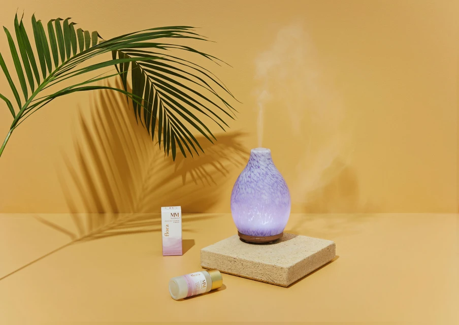 Aroma diffuser with essential oils on a beige background with palm leaf shadow. Interior wellness and home aromatherapy concept.
