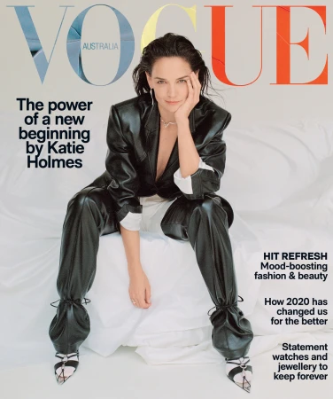 Katie Holmes seated on a white bed wearing a black leather suit with make-up by Linda Jefferyes