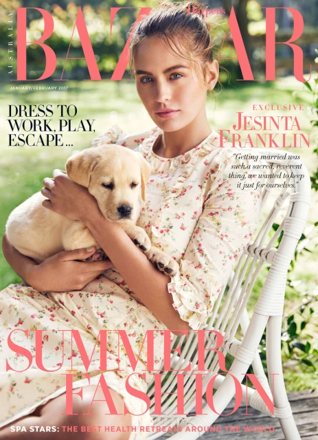 Magazine cover featuring a young adult woman holding a light yellow Labrador puppy, soft lighting, outdoor setting, promoting summer fashion.