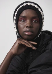 Close-up portrait of a black woman wearing a black embellished balaclava with pearls and rhinestones by makeup artist Linda Jefferyes.