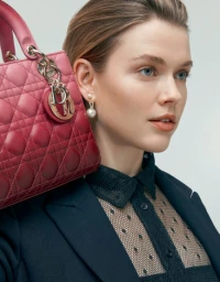 Woman in dark patterned blouse holding pink quilted handbag by Tane Coffin in Sydney