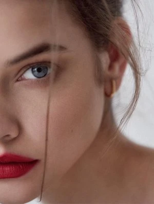 Close-up portrait of a woman with red lipstick and a gold hoop earring styled by Karla Clarke