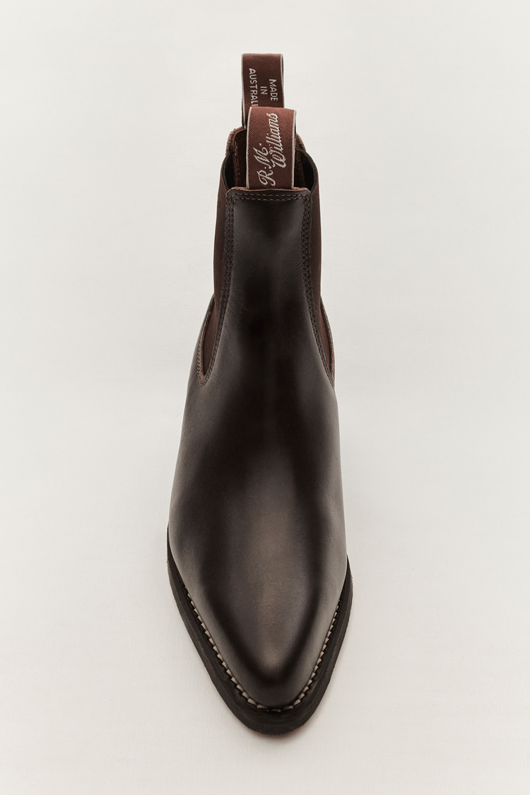 Dark brown leather Chelsea boot with elastic side panels and pointed toe on a clean white background in a studio setting. R.M. Williams.