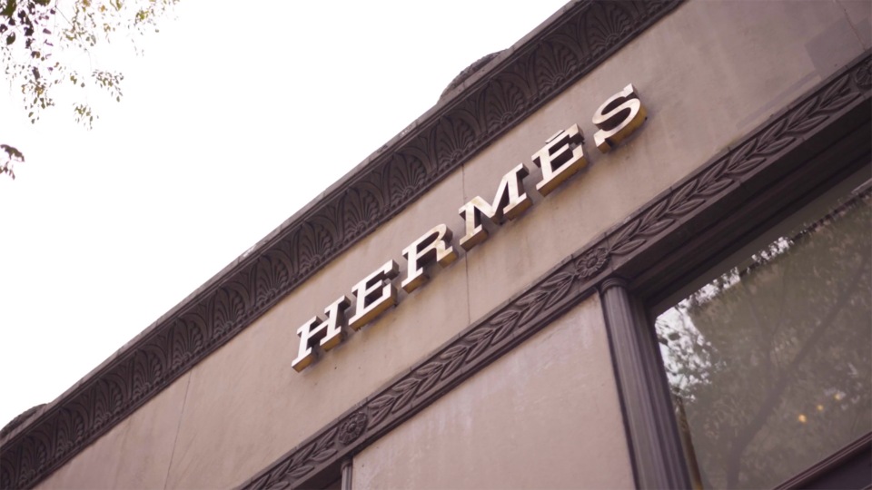 Hermès store facade featuring a prominent brand logo. The building has architectural details like molded trim and classic window design.
