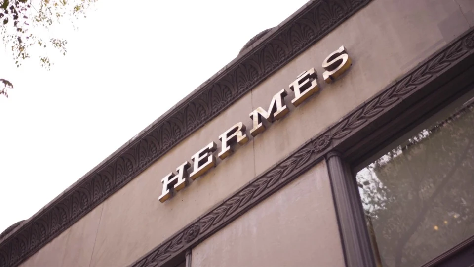 Hermès store facade featuring a prominent brand logo. The building has architectural details like molded trim and classic window design.