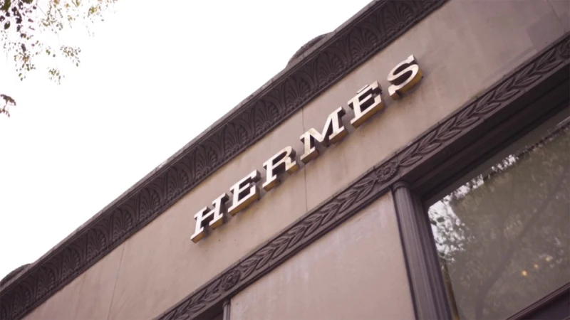 Hermès store facade featuring a prominent brand logo. The building has architectural details like molded trim and classic window design.