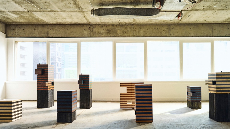 Architectural product photography showcasing striped wood block art pieces, interior design, and natural daylight in an empty space.