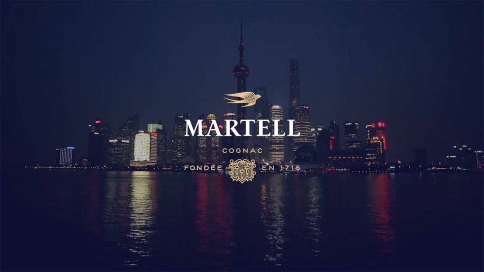 Cityscape view of the Shanghai skyline at night, featuring the Martell Cognac logo and branding in the foreground.