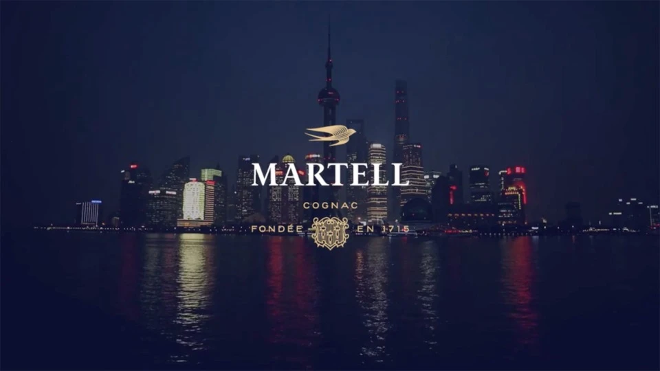 Cityscape view of the Shanghai skyline at night, featuring the Martell Cognac logo and branding in the foreground.