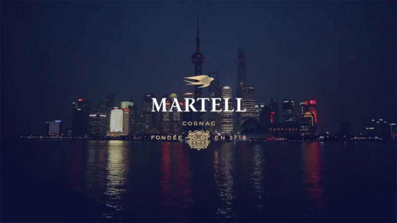 Cityscape view of the Shanghai skyline at night, featuring the Martell Cognac logo and branding in the foreground.
