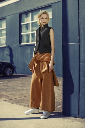 Model standing outdoors wearing a black vest and brown wide leg pants styled by Kate Gaskin in Sydney.