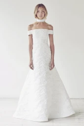 Model in a white off-the-shoulder textured gown and matching choker standing against a plain white background.