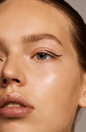 Close-up beauty portrait of a woman with graphic black eyeliner and glossy lips by make-up artist Molly Warkentin