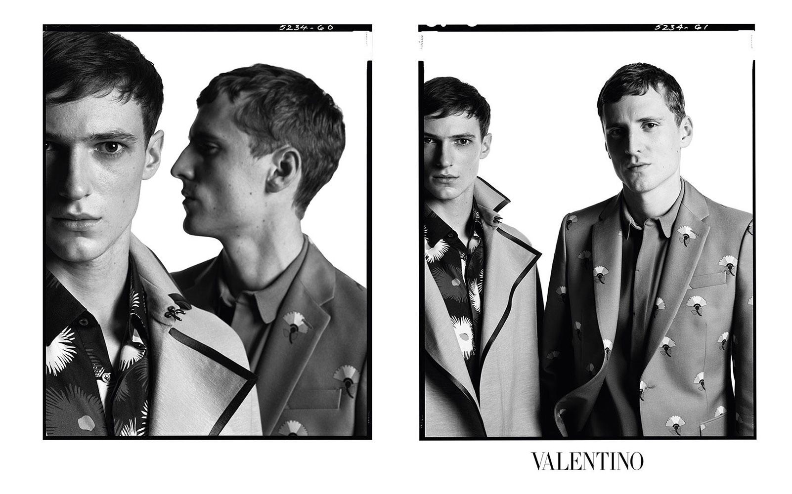 Black and white studio shot of two adult male fashion models wearing floral patterned shirts and suits posing against a white backdrop.