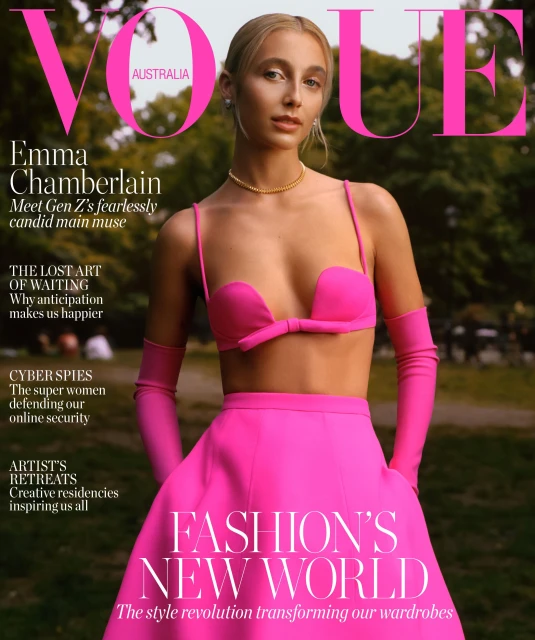 Vogue Australia cover featuring Emma Chamberlain in a bright pink skirt and top, posing in front of a blurred green background.