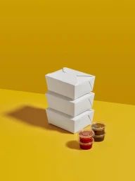 Stack of three white takeaway food boxes with small dipping sauce cups on a yellow background