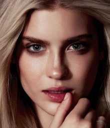 Close-up beauty portrait of a blonde woman with blue eyes touching her lips, photographed in Sydney.