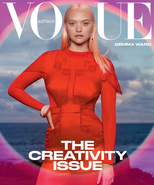Vogue Australia magazine cover featuring a young woman with strawberry blonde hair wearing an orange dress with a rainbow and ocean backdrop.