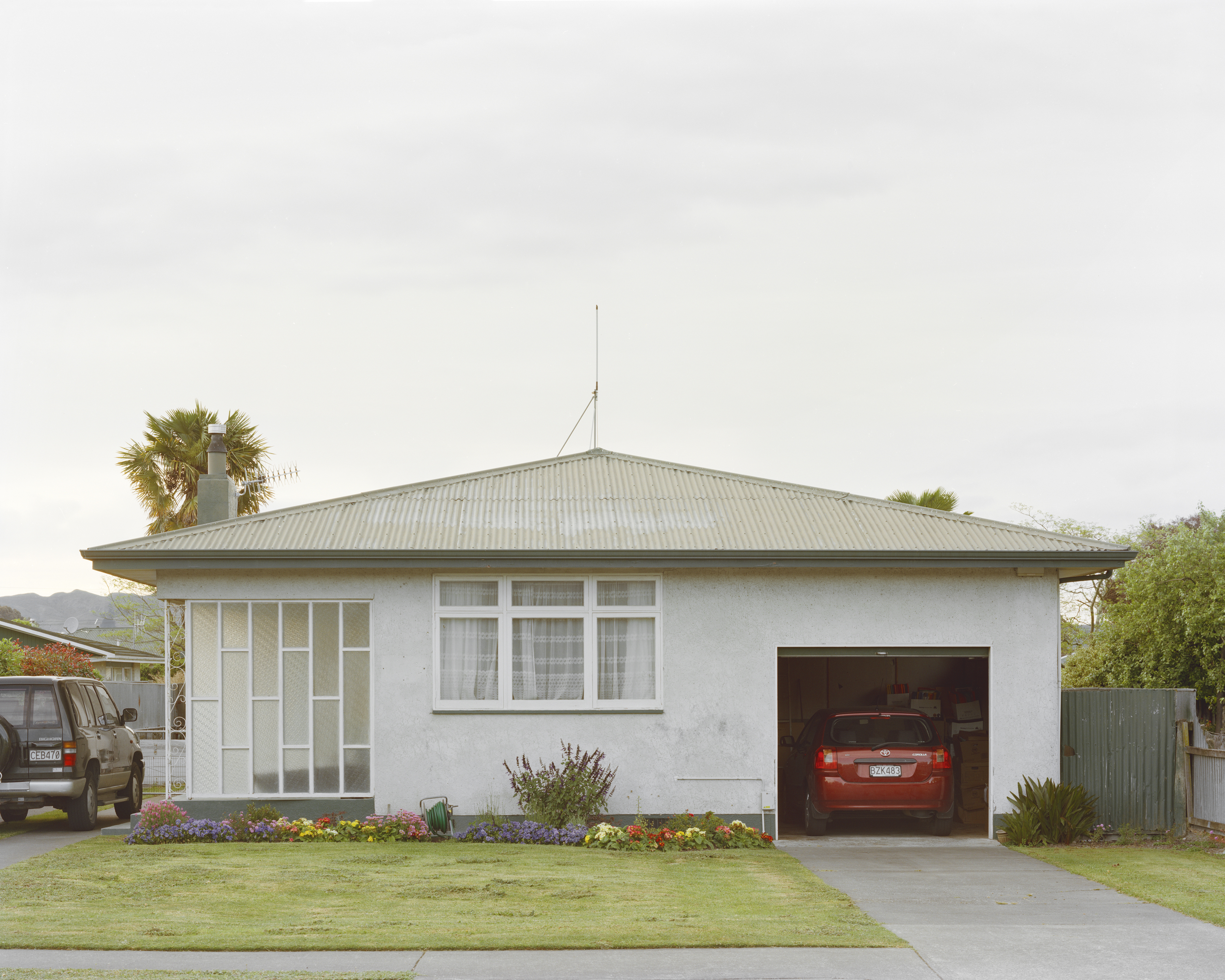 Residential house with a garage, lawn, and driveway, showcasing an SUV parked outside and another car inside the garage.