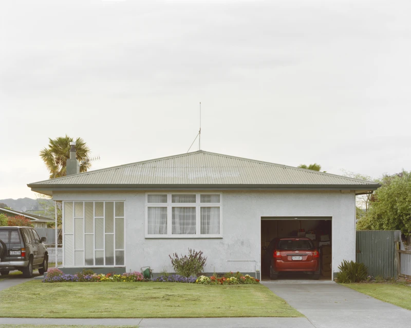 Residential house with a garage, lawn, and driveway, showcasing an SUV parked outside and another car inside the garage.