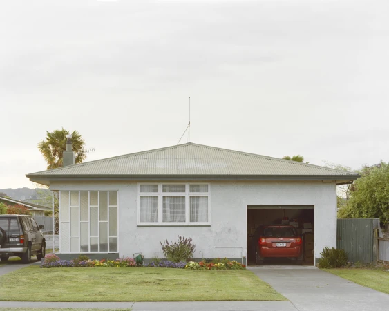 Residential house with a garage, lawn, and driveway, showcasing an SUV parked outside and another car inside the garage.