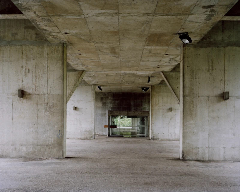 Concrete architectural structure featuring a covered outdoor space with light fixtures, offering a unique industrial aesthetic.