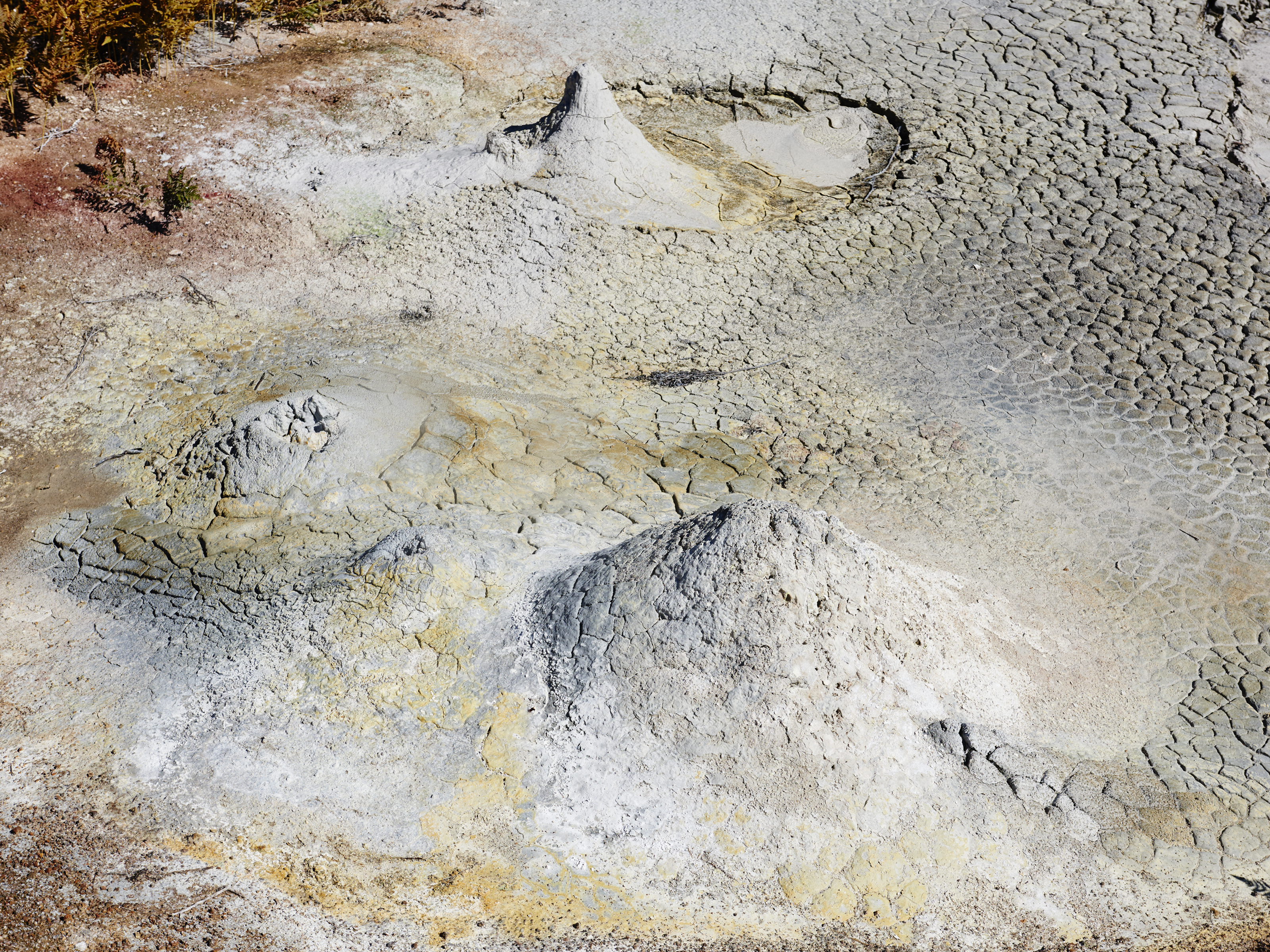 Overhead shot of a barren landscape with cracked earth and small mounds, showcasing arid environment and geological features.