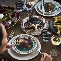 High-angle food photography of a dinner table laden with gourmet dishes, wine glasses, and decorated plates, captured by Jonny Valiant.
