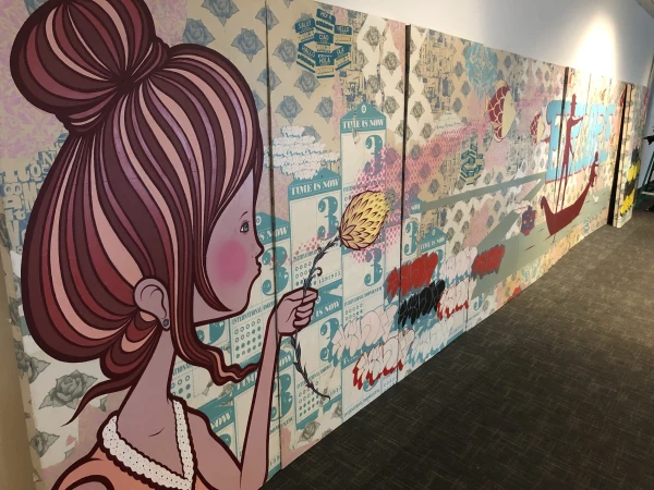 Art installation featuring a cartoon girl holding a flower against an elaborate background with text and floral patterns on multiple panels.