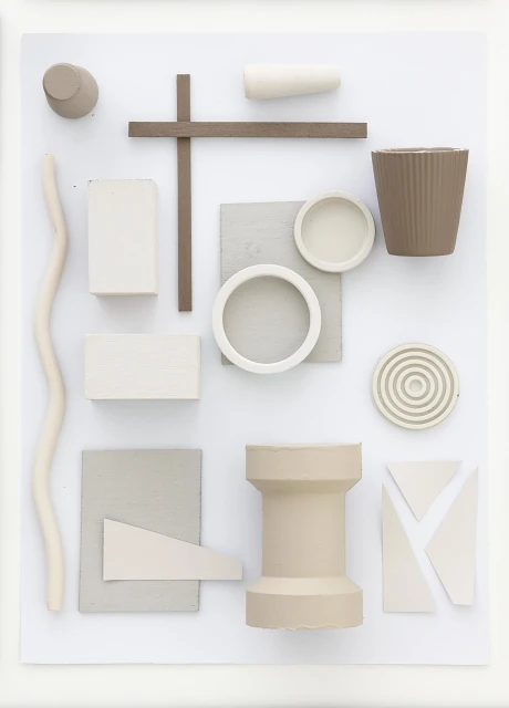 Arrangement of geometric shapes and objects in muted tones on a white background, creating a minimalist and abstract composition.