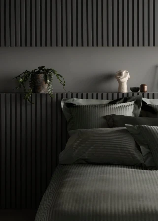 Bedroom interior with grey striped bedding, grey slatted wall paneling, potted plant, and decorative white head sculpture on shelf.