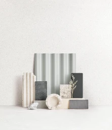 Minimalist material flat lay styling with textured stone blocks, corrugated grey panel, and dried botanical stems.