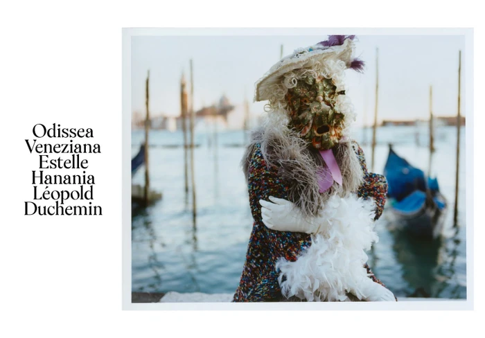 Costumed figure wearing a mask and white feathered hat with gondolas in the background by Estelle Hanania