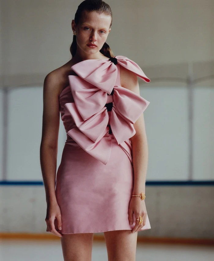 Model in a pink strapless mini dress adorned with large sculptural bows, captured by Estelle Hanania.